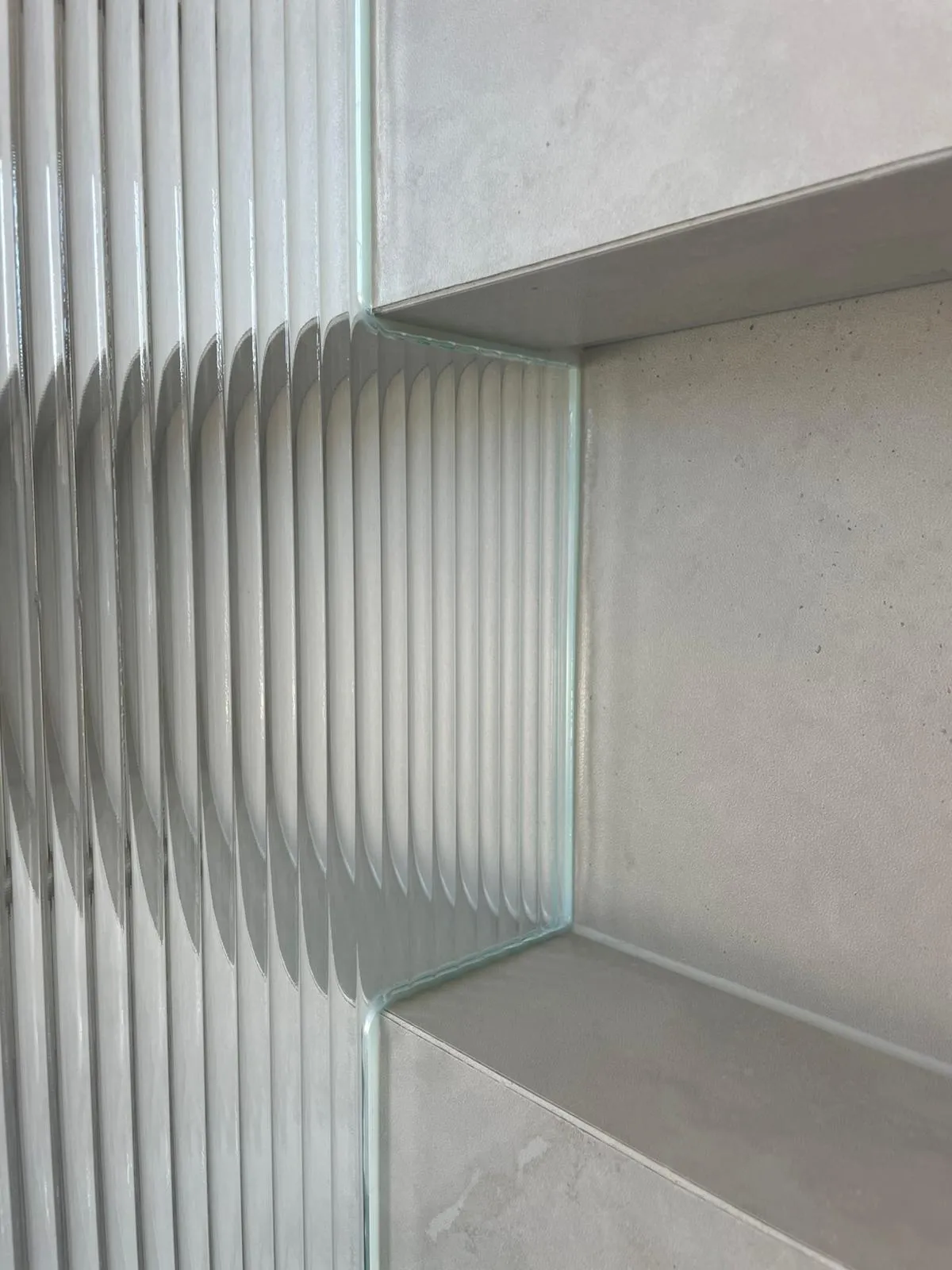 Daylight raking across the polished edge of stacked low-iron reeded glass